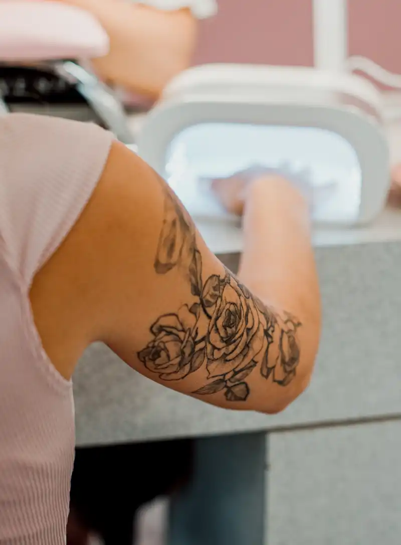 a client hardening her nails in a UV nail lamp