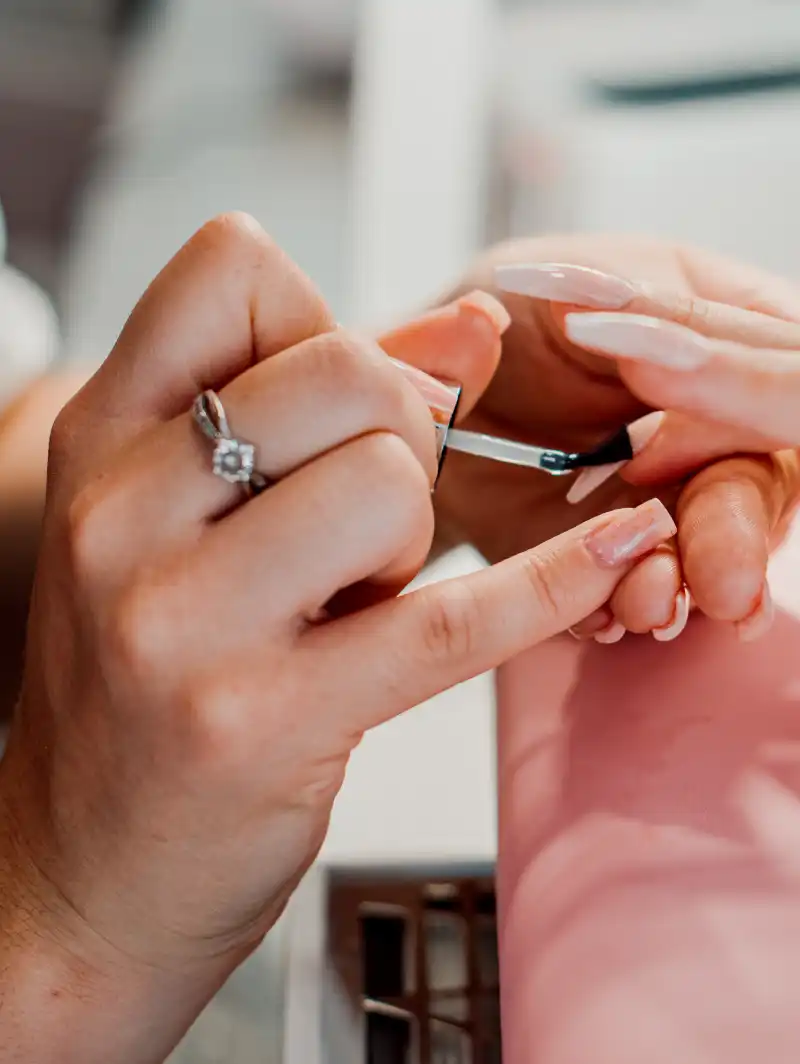 beautician painting a client's nails with nail polish